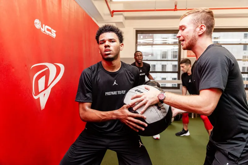 Matt coaching a young basketball player with a medicine ball at a Jordan Brand camp
